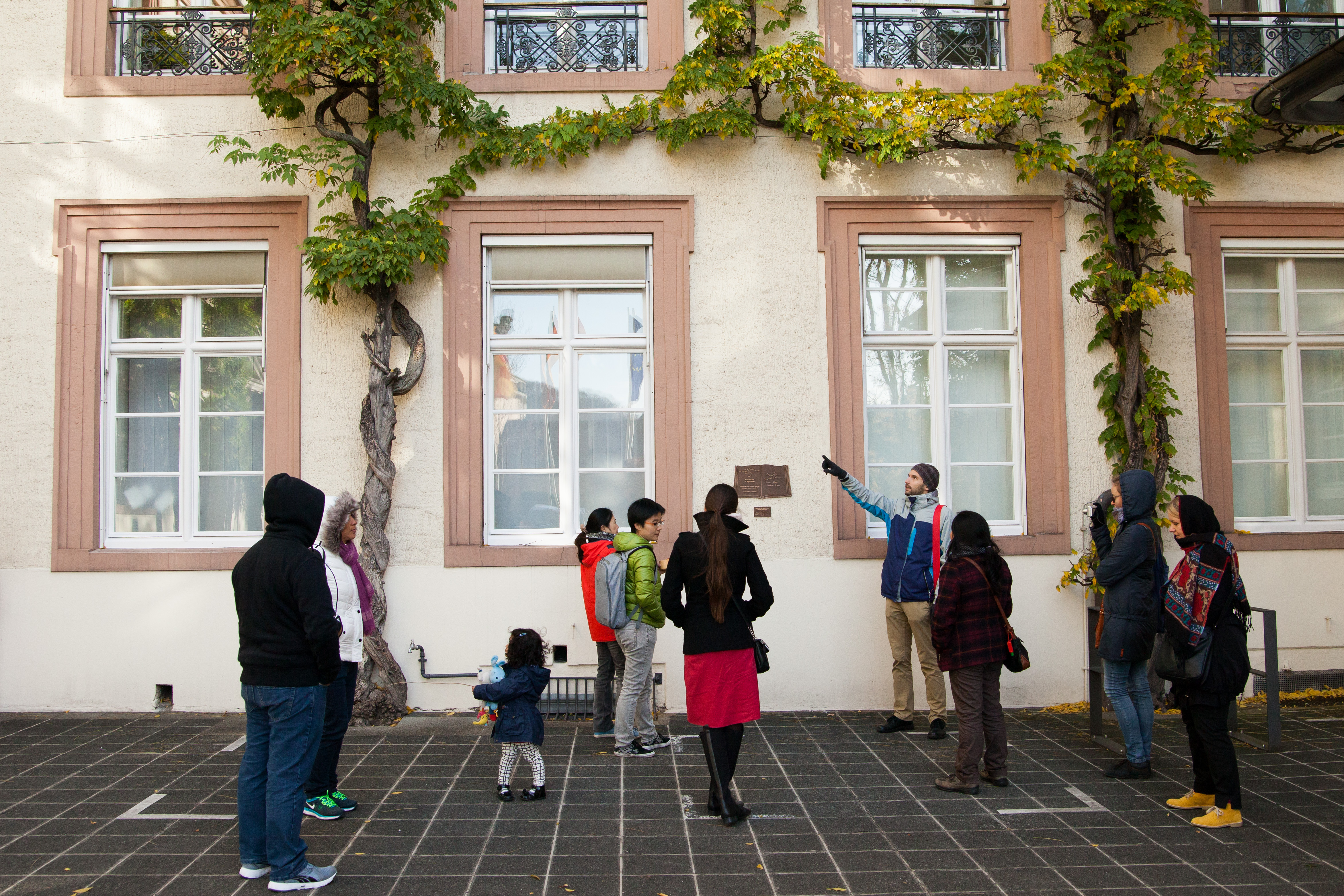 Tour Guide Pointing out a plaque on a building to his group of travelers.