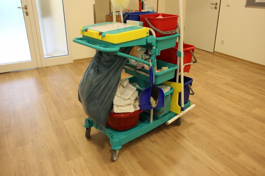 A hotel cleaning trolley in a hallway with wood floors.