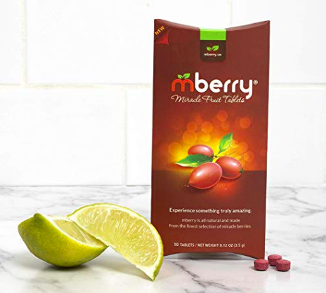 A box of mberry Miracle Berry Tablets on a white counter with 3 tablets and 2 slices of lime.