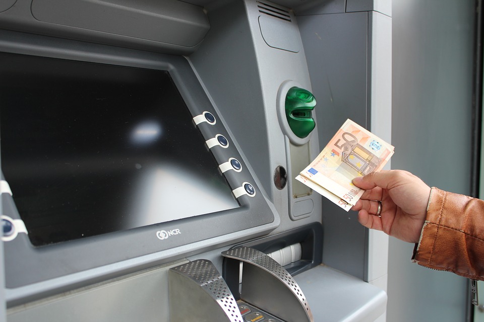 ATM screen with a hand holding two 50 euro notes.