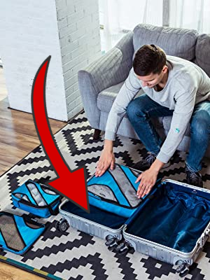 Man sitting on a couch packing a suitcase with packing cubes on the floor. A large red arrow points to unused space in the suitcase where a packing cube won't fit.