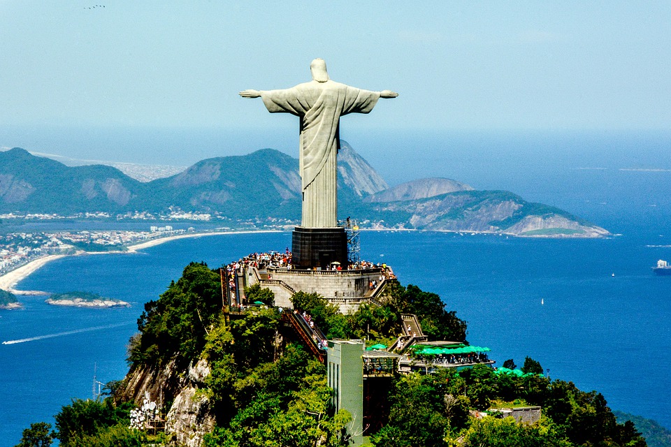 Christ the Redeemer statue from behind with the beach and mountains of Rio de Janeiro.