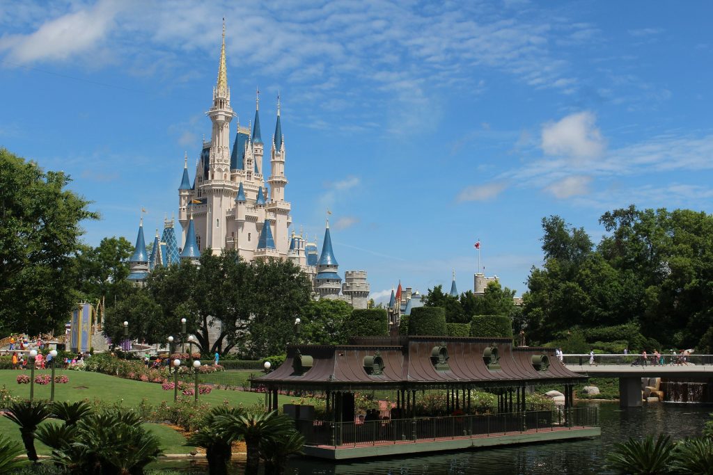 Cinderella's castle at Disney World from a distance with a green area and pond in the foreground.