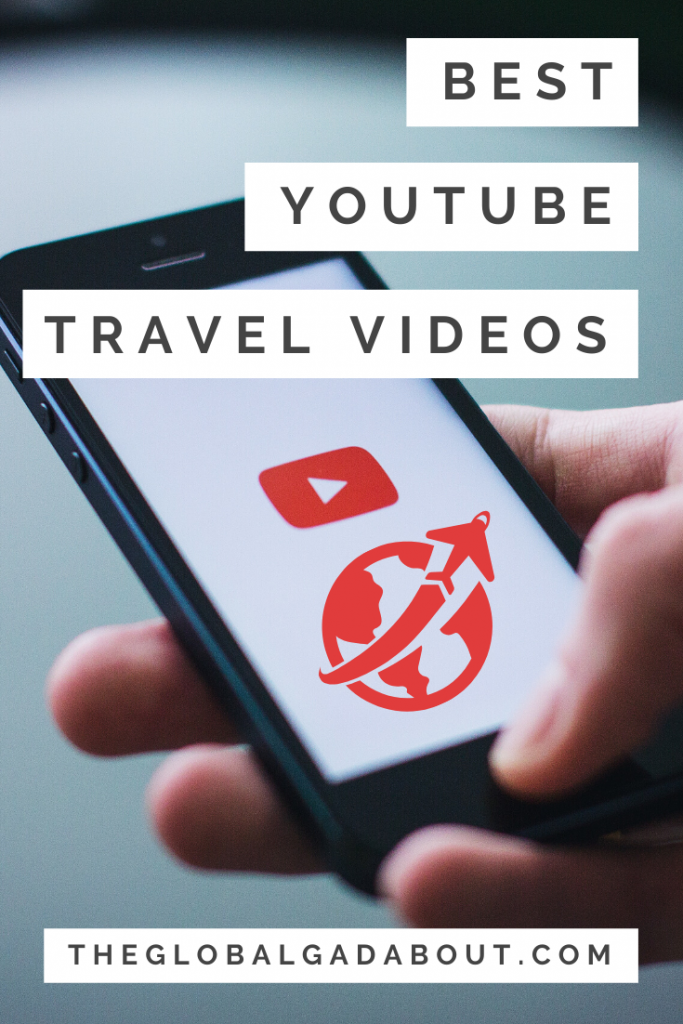 A hand holding a phone with a YouTube play symbol and a globe with an airplane symbol on the screen. The words "Best YouTube Travel Videos" and "TheGlobalGadabout.com" are superimposed with white boxes around them.