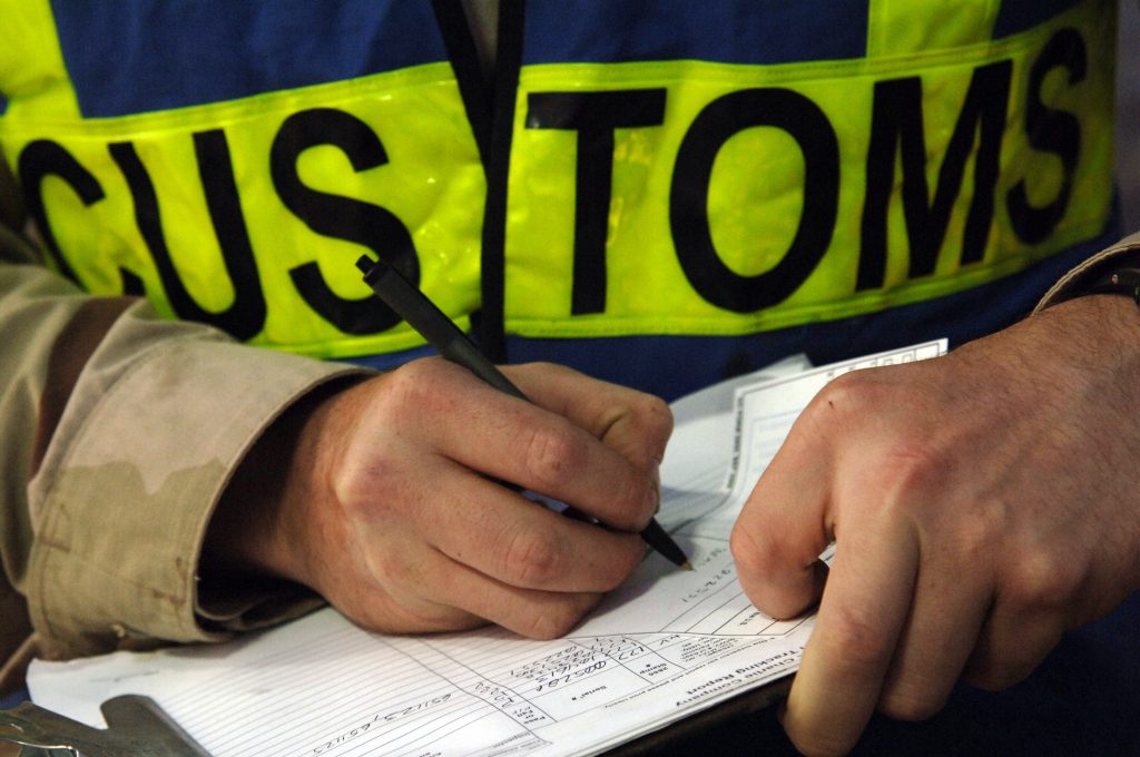 Close up on a customs official's hands filling out paperwork.